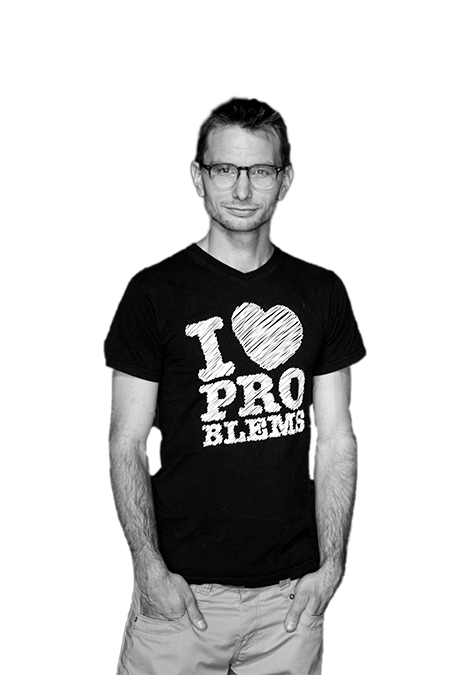 A black and white image of Steven. He is looking straight into the camera. He wears a shirt that says: 'I love Problems.'